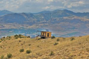 a small house on a hill with mountains in the background at Sareni in Areni