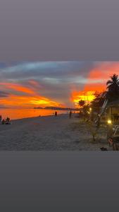 een zonsondergang op een strand met mensen op het zand bij Nomad Soul Bungalow in Ko Pha Ngan