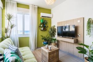 sala de estar con paredes verdes y TV de pantalla plana en Whispering Palms 1-BR Apt By Finikoudes Beach, en Lárnaca