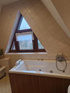 ein Badezimmer mit einer großen Badewanne und einem Fenster in der Unterkunft Mikołajówka - przytulny dom z widokiem in Świeradów-Zdrój + 8 Fotos