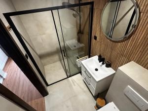 a bathroom with a shower and a sink and a mirror at Penzión Kocka in Hnúšťa