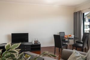 Una sala de estar con televisión y una mesa con sillas. en Golden Star AU by An Island Apart, en Funchal