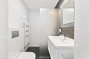 a white bathroom with a toilet and a sink at B's Strandappartementen in Domburg +46 photos