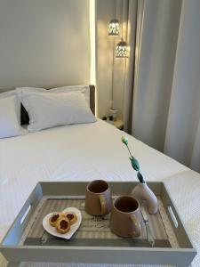 ein Tablett mit zwei Tassen und einem Teller Essen auf einem Bett in der Unterkunft Luxury apartment 70m2 with 2 bedrooms ,balcony and jacuzzi , Downtown Thessaloniki in Thessaloniki