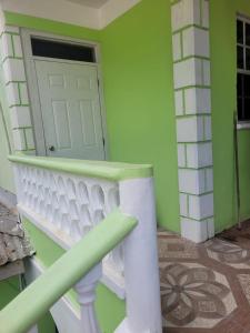 a green room with a white door and a staircase at J and N cozy quarters in Roseau +1 photo