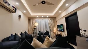 a living room with blue couches and a ceiling at Elysium Luxe Stays Facing Cenaturus Mall Islamabad in Islamabad