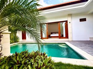 a swimming pool in front of a house at Lacok Villa in Cemagi