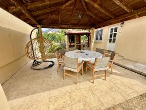 Un patio con mesa y sillas y un columpio. en Sunny village, pool house, en Podgorica
