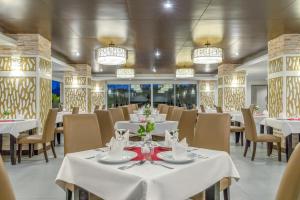 un restaurante con mesas y sillas blancas y lámparas de araña en Chanalai Hillside Resort, Karon Beach en Karon