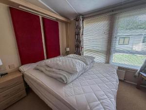 グレート・ヤーマスにあるBeautiful 6 Berth Lodge At Cherry Tree Holiday Park Ref 70002Tgの白いシーツと窓のあるベッドのある寝室