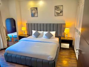 a bedroom with a large bed with two tables and two lamps at Elysium Luxe Stays Facing Cenaturus Mall Islamabad in Islamabad