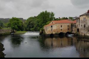 a river with a bridge and some buildings and water at Real 49 camiño Santiago in Neda