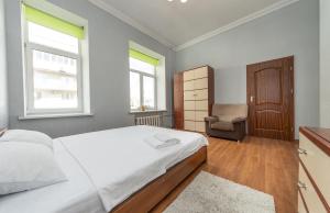 基辅Простора 3 кімнатна біля Майдану Незалежності的一间卧室，里面有一张床、一把椅子和两扇窗户