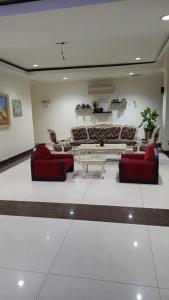 a living room with two red chairs and a table at Wisma Davinci Sabrina in Jakarta