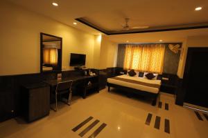 a room with a bed and a desk and a television at Nakshatra Hotel in Bānswāra +26 photos