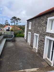 a stone house with white windows and a driveway at Casa Herbarium in Prazeres