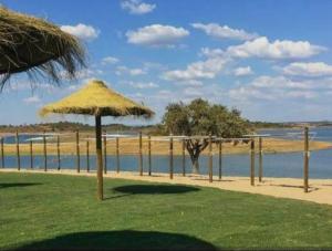 a beach with two umbrellas and a body of water at O Refúgio in Reguengos de Monsaraz