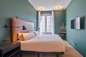 a bedroom with a large white bed and a window at Uma Suites Atocha in Madrid