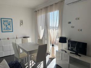 a white dining room with a table and a window at Seaside apartments Casa CARLA e Casa ANDREA in Olbia