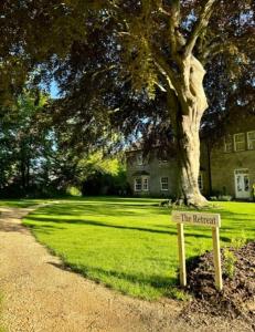 a sign for the retreat in front of a tree at Luxury Retreat at The Old Rectory in Babcary +4 photos