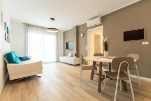 a living room with a table and chairs and a living room at Sun Beach Residence con Piscina - Piazza Brescia - Adria Holiday Jesolo - FAMILY APARTMENTS in Lido di Jesolo
