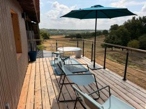a deck with a table and chairs and an umbrella at Loft élégant au cœur de la campagne avec SPA privé in Mauvezin