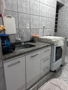 a white kitchen with a sink and a microwave at Apartamento Doce Alegria in Sao Jose do Rio Preto