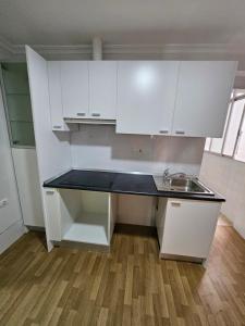 a small kitchen with white cabinets and a sink at Apto en San Antonio a un paso de la playa in Cullera