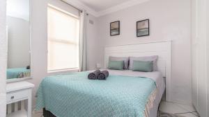 a white bedroom with a bed with a blue comforter at Hermanus Beach Club in Hermanus