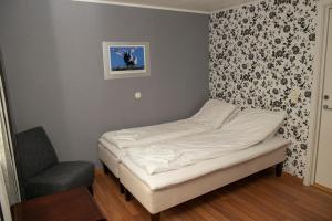 a small bed in a room with a chair at Ulvsvåg Gjestgiveri og Fjordcamping AS in Ulvsvåg