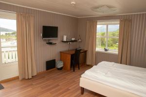 a bedroom with a bed and a desk and a television at Ulvsvåg Gjestgiveri og Fjordcamping AS in Ulvsvåg