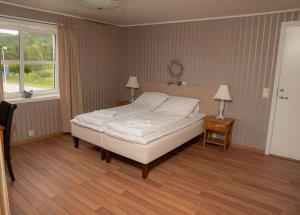 a bedroom with a bed and two lamps and a window at Ulvsvåg Gjestgiveri og Fjordcamping AS in Ulvsvåg