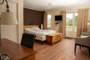 a hotel room with a bed and a table and chairs at Ulvsvåg Gjestgiveri og Fjordcamping AS in Ulvsvåg