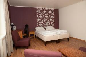 a bedroom with a bed and a chair in it at Ulvsvåg Gjestgiveri og Fjordcamping AS in Ulvsvåg