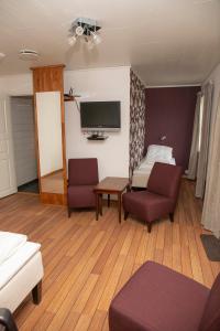 a living room with a couch and a bed and a tv at Ulvsvåg Gjestgiveri og Fjordcamping AS in Ulvsvåg