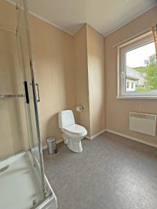 a bathroom with a toilet and a window at Ulvsvåg Gjestgiveri og Fjordcamping AS in Ulvsvåg
