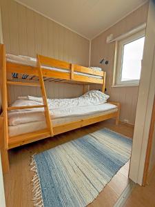a bedroom with two bunk beds and a rug at Ulvsvåg Gjestgiveri og Fjordcamping AS in Ulvsvåg