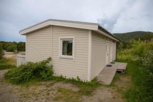 a small white building with a porch and a bench at Ulvsvåg Gjestgiveri og Fjordcamping AS in Ulvsvåg