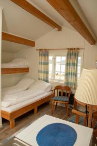 a bedroom with two beds and a chair and a table at Ulvsvåg Gjestgiveri og Fjordcamping AS in Ulvsvåg