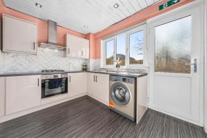 una cucina con mobili bianchi, lavatrice e asciugatrice di Quirky, Family Home in Glasgow a Cardonald Altre 40 foto
