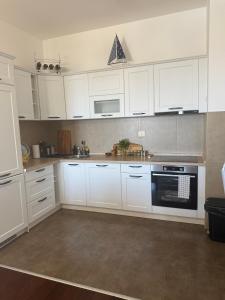 a kitchen with white cabinets and a black oven at Sargo Apartman Bar in Bar