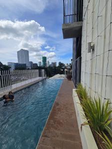 un hombre nadando en una piscina al lado de un edificio en Ohana Suites 2 Studio Lot 8 Condo Near Ayala Cebu City with fast Wifi and Netflix, en Cebú