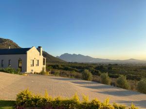 a white building on a road with mountains in the background at Sneeukop Mountain Cottage in Paarl