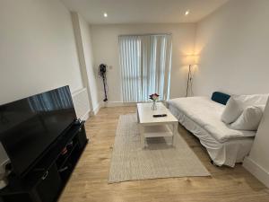 a living room with a couch and a flat screen tv at London Luton Airport Luxury Midland Apartments - GATED PARKING - Balcony - Sleeps 4 in Luton