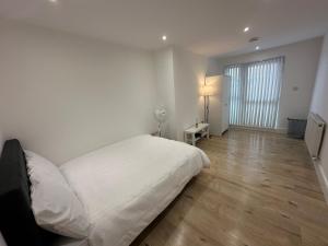 a bedroom with a white bed and a wooden floor at London Luton Airport Luxury Midland Apartments - GATED PARKING - Balcony - Sleeps 4 in Luton