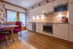 a kitchen with white cabinets and a wooden table at Chasa Baschenowa in Kappl