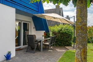 a table and chairs with an umbrella on a patio at Haus Lotte in Wittmund