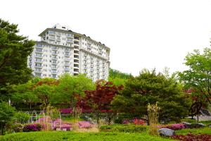 a tall apartment building in the middle of a park at Elysian Gangchon Resort in Chuncheon