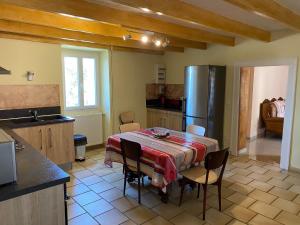 a kitchen with a table with chairs and a refrigerator at Les Tilleuls in Tréjouls