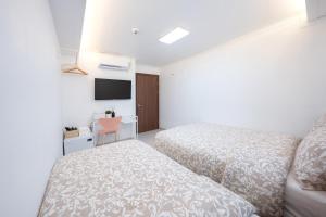 Una habitación de hotel con dos camas y un televisor. en Seoul Cozy Hostel, en Seúl